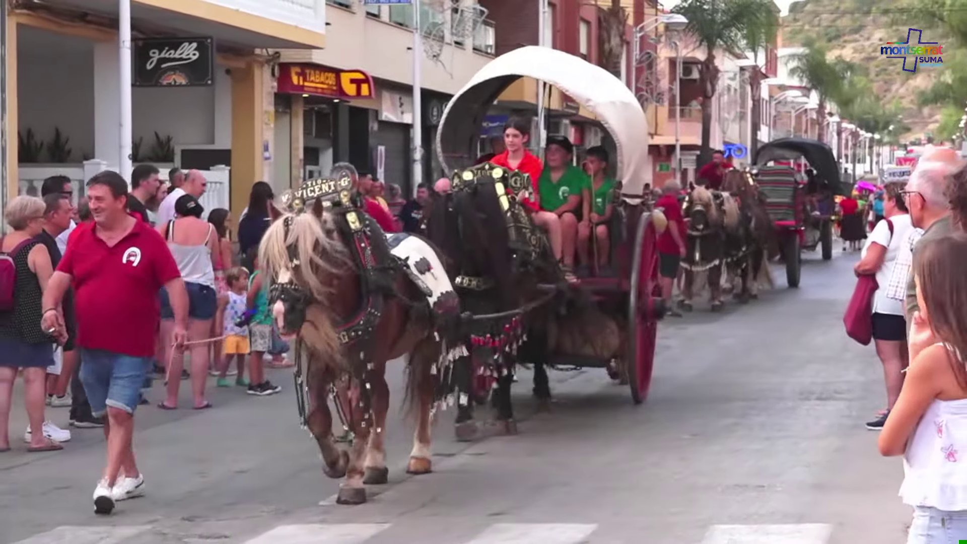 Carroza tirada por dos caballos durante la Gran Cavalcada de Festes de Montserrat, con el público siguiendo la comitiva por las calles del pueblo